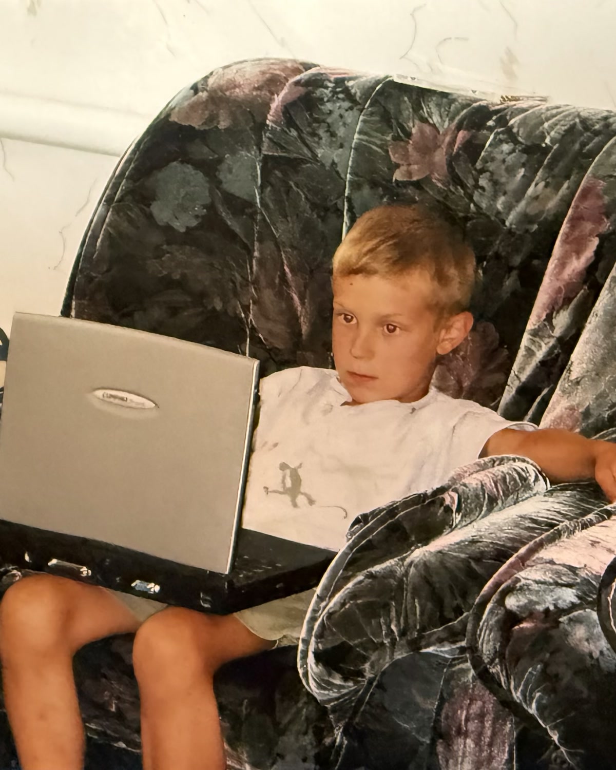 Antoni Kozelski as a child, sitting on a sofa with a laptop